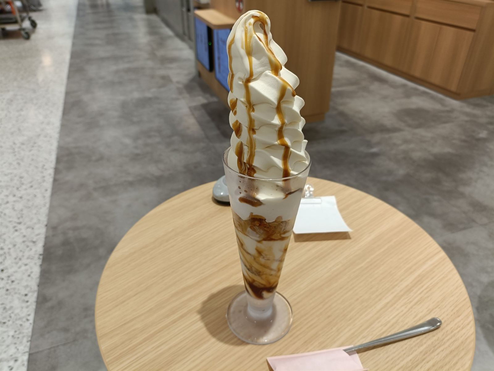 背の高いグラスに、ソースがかかったソフトクリームが高く盛られたパフェ