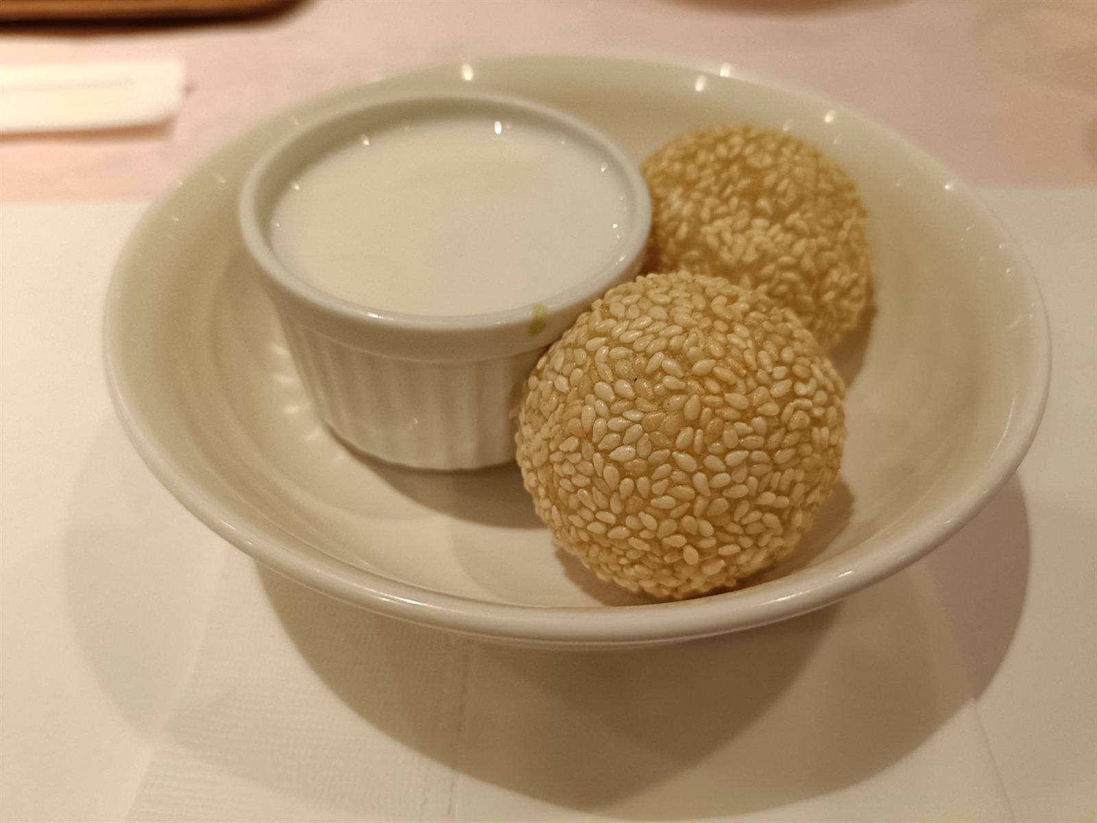 白い器に入った杏仁豆腐と、白ごまがびっしりついたゴマ団子2つ